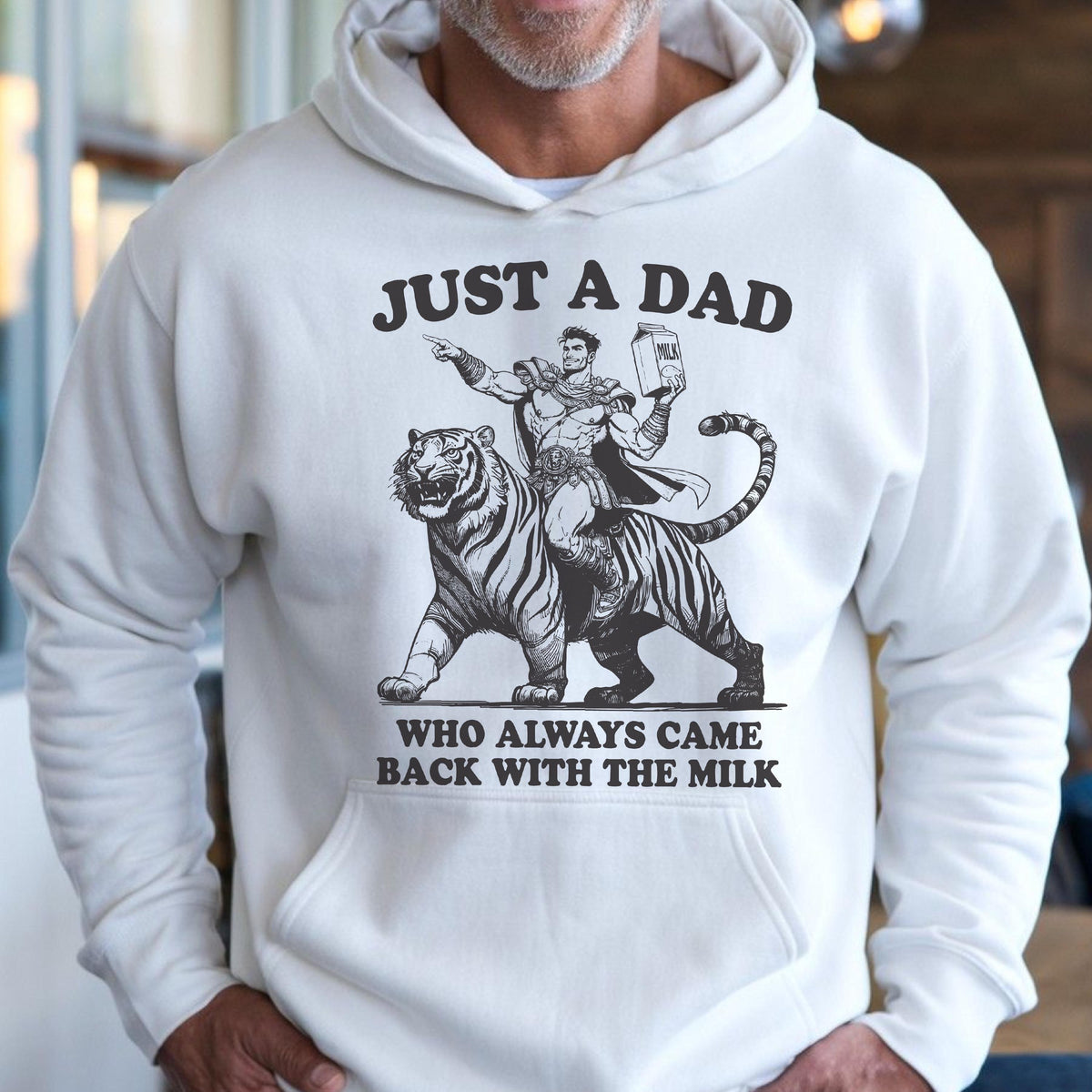 May include: White hoodie with a graphic design. The design features the text "JUST A DAD" above an illustration of a man riding a tiger, holding a milk carton, with the text "WHO ALWAYS CAME BACK WITH THE MILK" below.