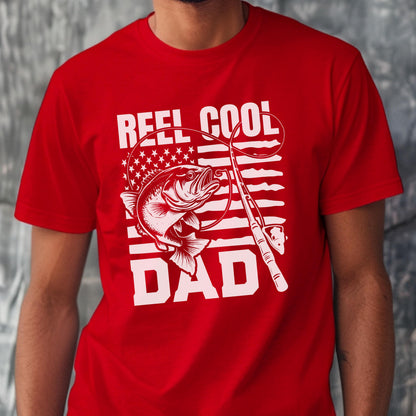May include: Red t-shirt with a white graphic featuring a fish, fishing rod, and the words "REEL COOL DAD." The design incorporates an American flag motif, with stars and stripes. The shirt is a solid red color.