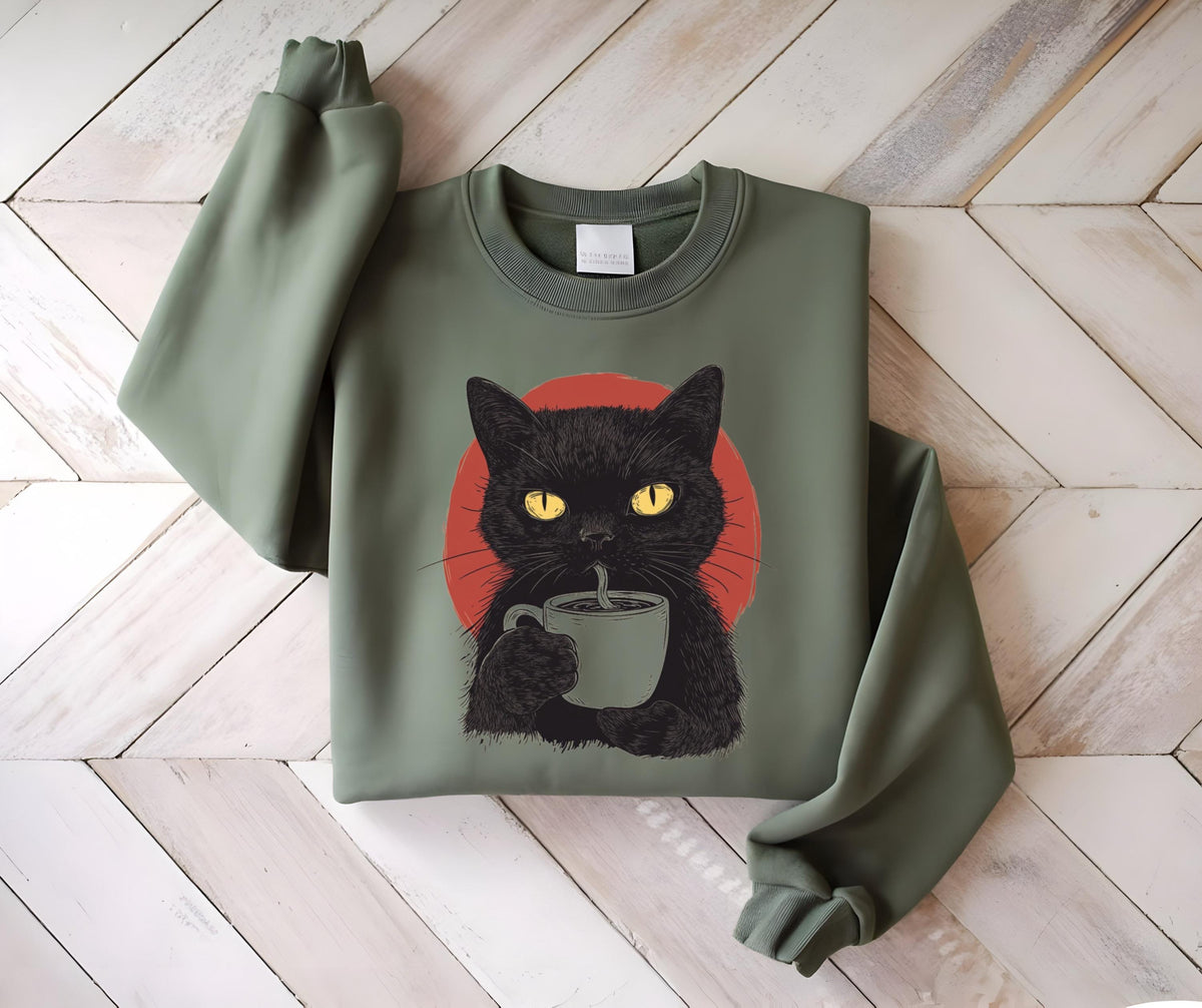 May include: An olive green crewneck sweatshirt featuring a graphic print of a black cat with bright yellow eyes holding a light gray mug. Behind the cat is a solid red circle. The sweatshirt has long sleeves and a ribbed collar and cuffs.