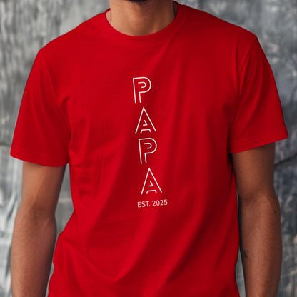 May include: A red t-shirt with the word "PAPA" in white, stylized lettering. Below the word "PAPA" is the text "EST. 2025". The shirt is short-sleeved.