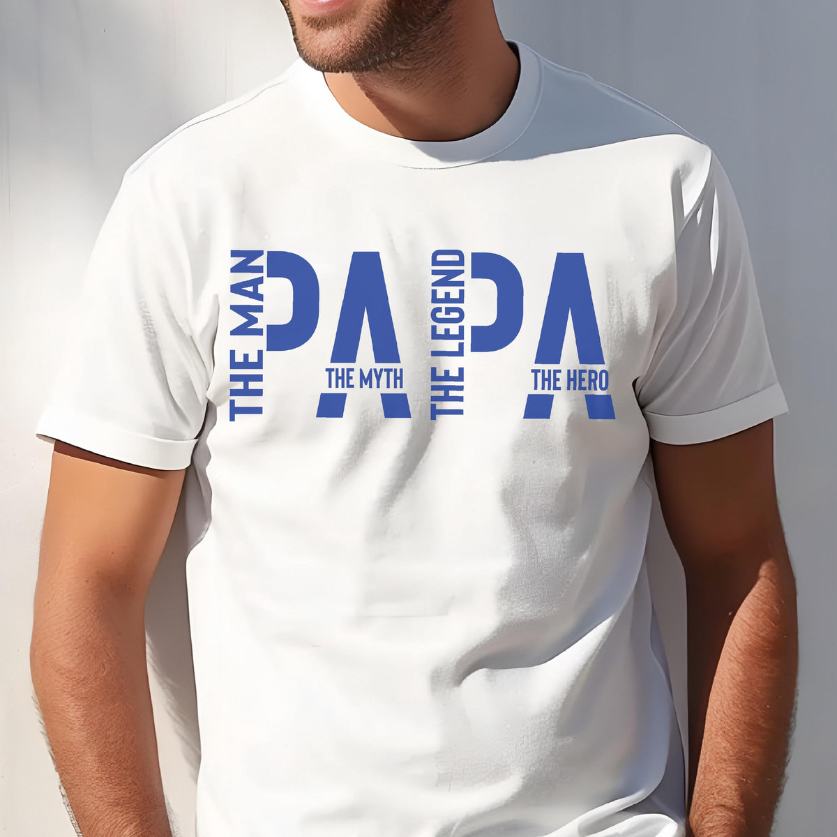 May include: White t-shirt with the word "PAPA" in large blue letters. The text "THE MAN", "THE MYTH", "THE LEGEND", and "THE HERO" are also printed on the shirt in blue. The shirt has short sleeves.
