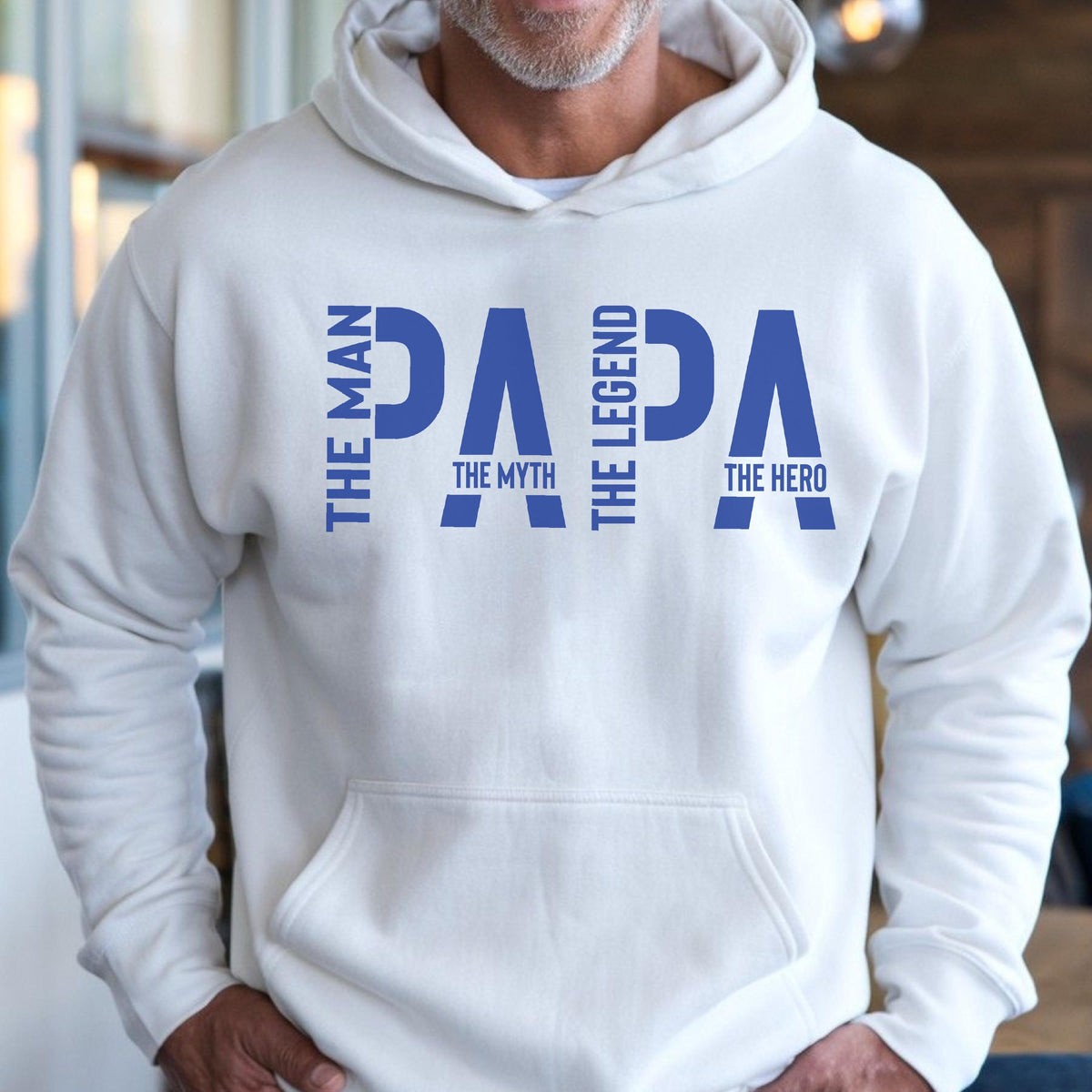May include: White hooded sweatshirt with the word "PAPA" in blue, with the phrases "THE MAN", "THE MYTH", "THE LEGEND", and "THE HERO" in blue. The sweatshirt has a front pocket and a drawstring hood.