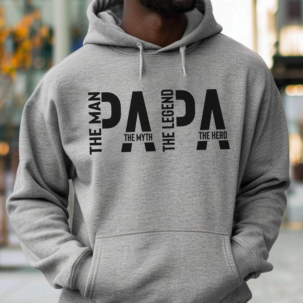 May include: A gray hooded sweatshirt with the word "PAPA" in large black letters. The words "THE MAN", "THE MYTH", "THE LEGEND", and "THE HERO" are vertically aligned on the left and right sides of the word "PAPA".