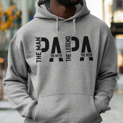 May include: A gray hooded sweatshirt with the word "PAPA" in large black letters. The words "THE MAN", "THE MYTH", "THE LEGEND", and "THE HERO" are vertically aligned on the left and right sides of the word "PAPA".