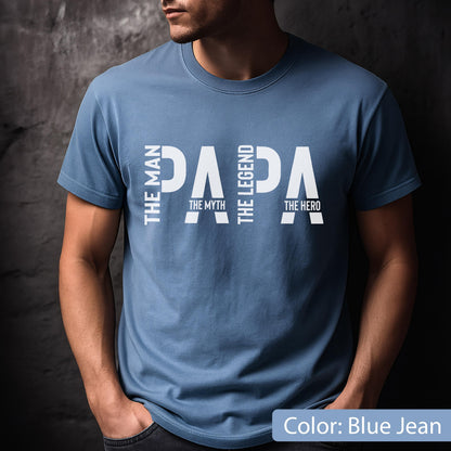 May include: Blue jean-colored t-shirt with the word "PAPA" in large white letters. The words "THE MAN", "THE MYTH", "THE LEGEND", and "THE HERO" are vertically aligned on the left and right sides of the word "PAPA".