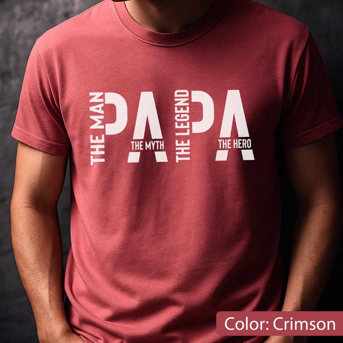 May include: Crimson-colored t-shirt with the word "PAPA" in large white letters. The words "THE MAN", "THE MYTH", "THE LEGEND", and "THE HERO" are arranged vertically on either side of the word "PAPA". The shirt is a solid color.