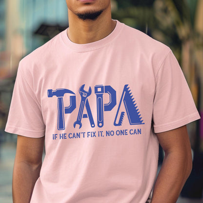 May include: A light pink t-shirt with the word "PAPA" in blue, designed with tool graphics. Below the word is the text "IF HE CAN'T FIX IT, NO ONE CAN". The shirt is made of a soft material.
