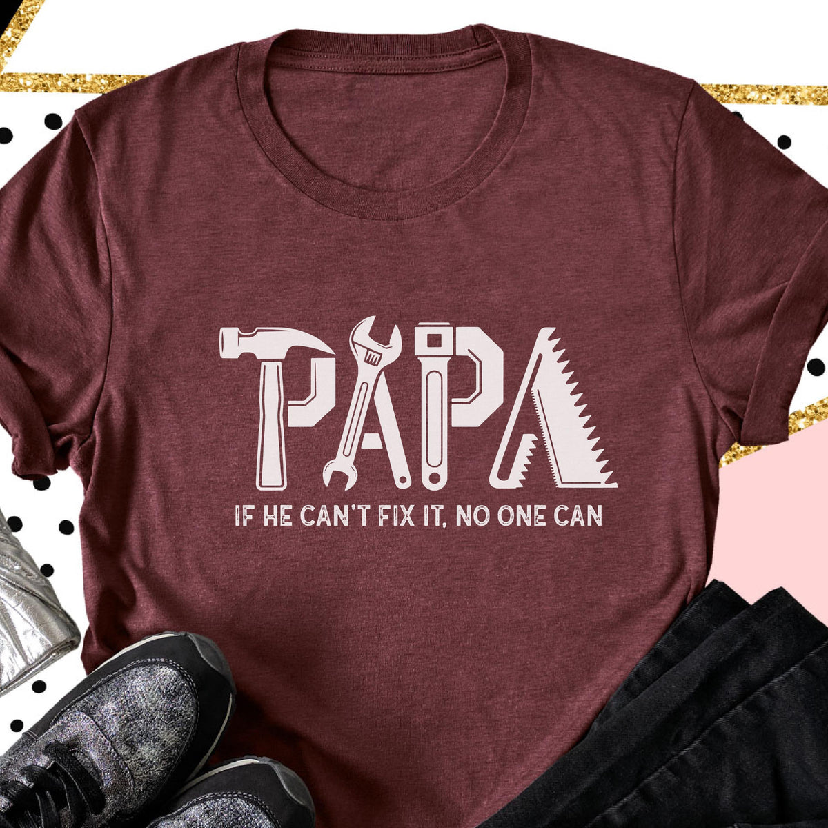 May include: Maroon t-shirt with the word "PAPA" in white, each letter designed as a tool: hammer, wrench, screwdriver, and saw. Below the word is the text "IF HE CAN'T FIX IT, NO ONE CAN."