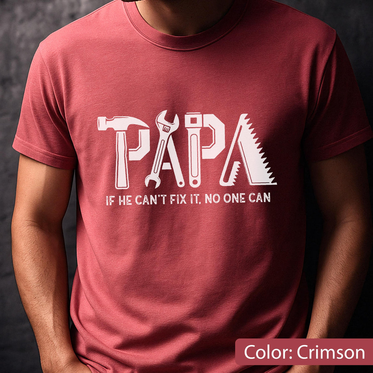 May include: Crimson-colored t-shirt with the word "PAPA" in white, designed with tool graphics. Below the word "PAPA" is the text "IF HE CAN'T FIX IT, NO ONE CAN". The shirt is a solid color.