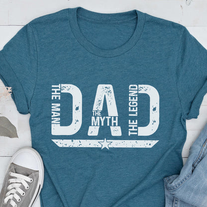 May include: Teal t-shirt with the words "DAD" in large white letters. The text "THE MAN, THE MYTH, THE LEGEND" is also printed on the shirt. A star graphic is below the word "MYTH".