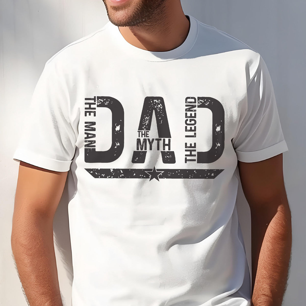 May include: White t-shirt with a distressed black graphic that reads "DAD The Myth The Legend". The text is arranged vertically on the sides and horizontally in the center, with a star design below.