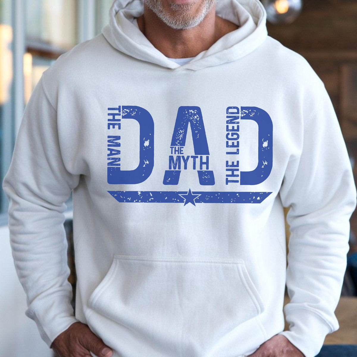 May include: White hoodie with a front graphic in blue that reads "DAD THE MAN THE MYTH THE LEGEND" with a star graphic. The hoodie has a front pocket and a drawstring hood.
