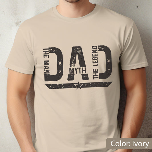 May include: Ivory-colored t-shirt with a distressed black graphic that reads "DAD" with "THE MAN", "THE MYTH", and "THE LEGEND" in a vertical arrangement. A star is centered below the word "DAD".