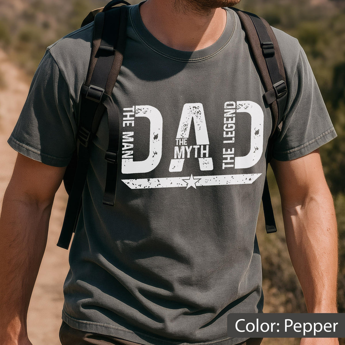 May include: Pepper-colored t-shirt with the text "DAD THE MYTH THE LEGEND THE MAN" in distressed white lettering. A star graphic is centered below the word "MYTH". The shirt has short sleeves and a crew neck.