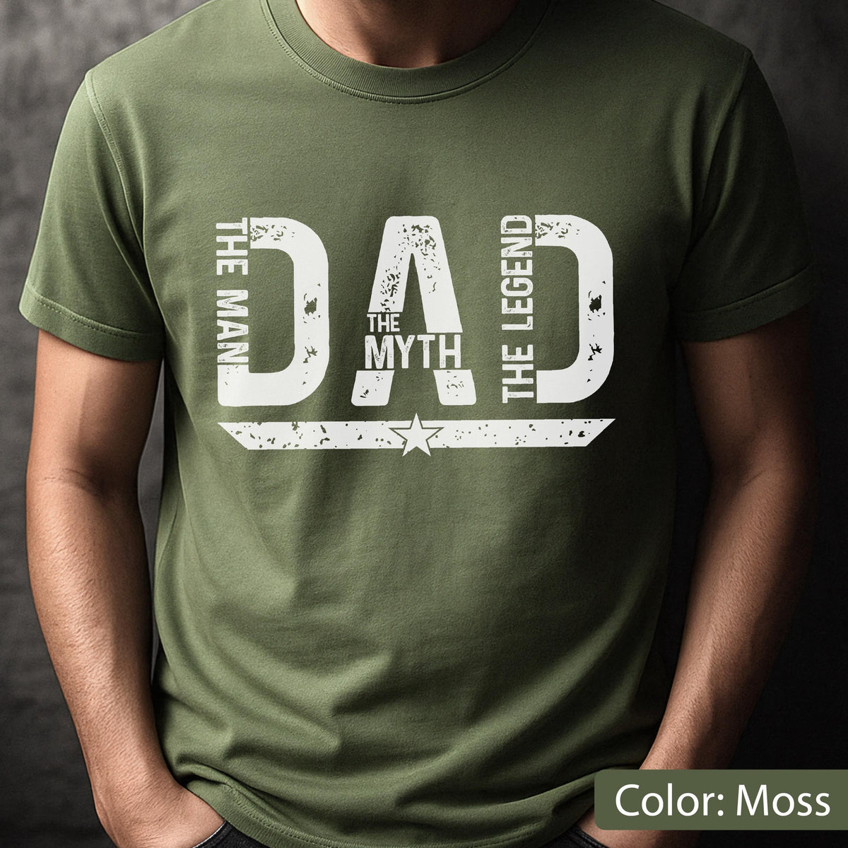 May include: Moss green t-shirt with the text "DAD THE MYTH THE LEGEND" in distressed white lettering. A star graphic is centered below the word "MYTH". The shirt is a solid color and has short sleeves.