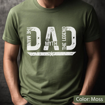 May include: Moss green t-shirt with the text "DAD THE MYTH THE LEGEND" in distressed white lettering. A star graphic is centered below the word "MYTH". The shirt is a solid color and has short sleeves.