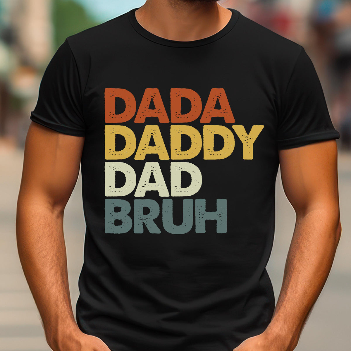 May include: Black t-shirt with the words "DADA DADDY DAD BRUH" in a retro font. The text is stacked vertically, with each word in a different color: orange, yellow, off-white, and teal.