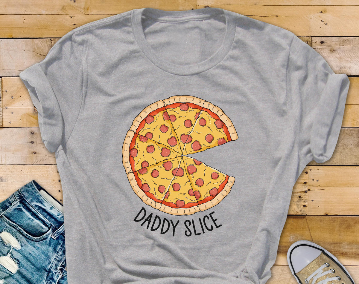 May include: A light gray t-shirt featuring a pizza graphic with a slice removed. The pizza has a yellow crust, red sauce, and pepperoni. The text "DADDY SLICE" is printed below the pizza in black.