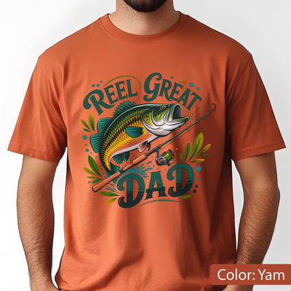 May include: Orange t-shirt with a fishing-themed graphic. The design features a detailed illustration of a fish, fishing rod, and the words "Reel Great Dad" in a stylized font. The shirt is a solid color.
