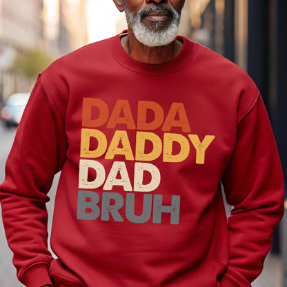 May include: A red sweatshirt with the words "DADA DADDY DAD BRUH" in a layered, retro font. The text is in shades of orange, yellow, gray, and white. The sweatshirt is a solid color and has long sleeves.