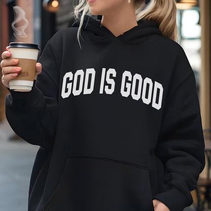 May include: Black hoodie with the text "GOD IS GOOD" in bold white letters across the chest. The hoodie has a drawstring hood and a kangaroo pocket. A person is holding a coffee cup.