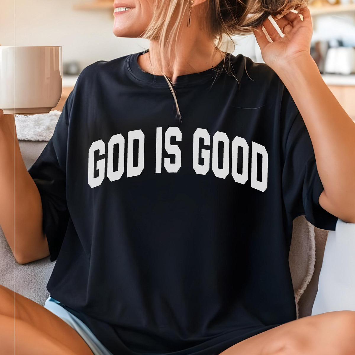May include: Black t-shirt with the white text "GOD IS GOOD". The shirt is a crew neck style and appears to be made of a soft material. The shirt is being worn by a person.