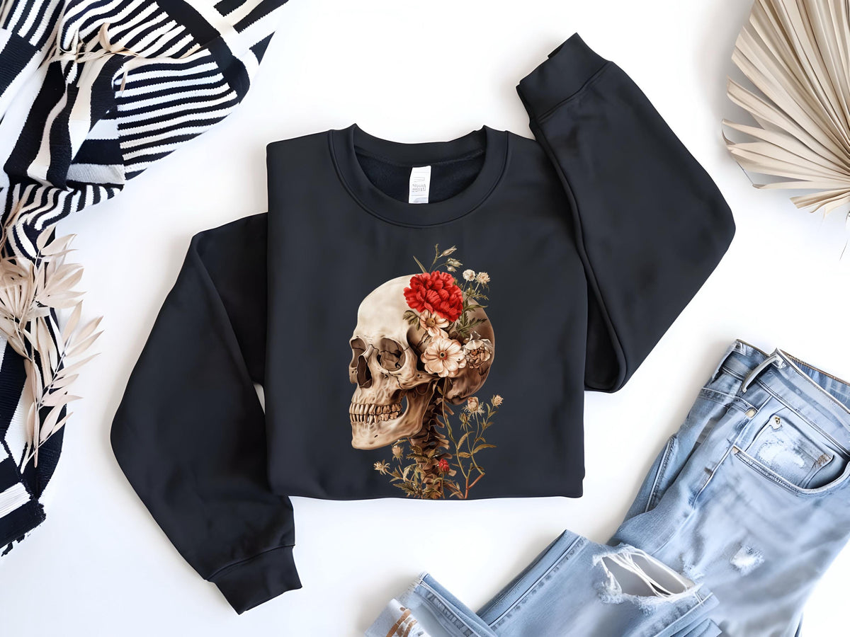 May include: Black sweatshirt with a floral skull design. The skull is white with black eye sockets and a red flower on top. The flowers are white and red and are arranged around the skull. The sweatshirt is on a white background.