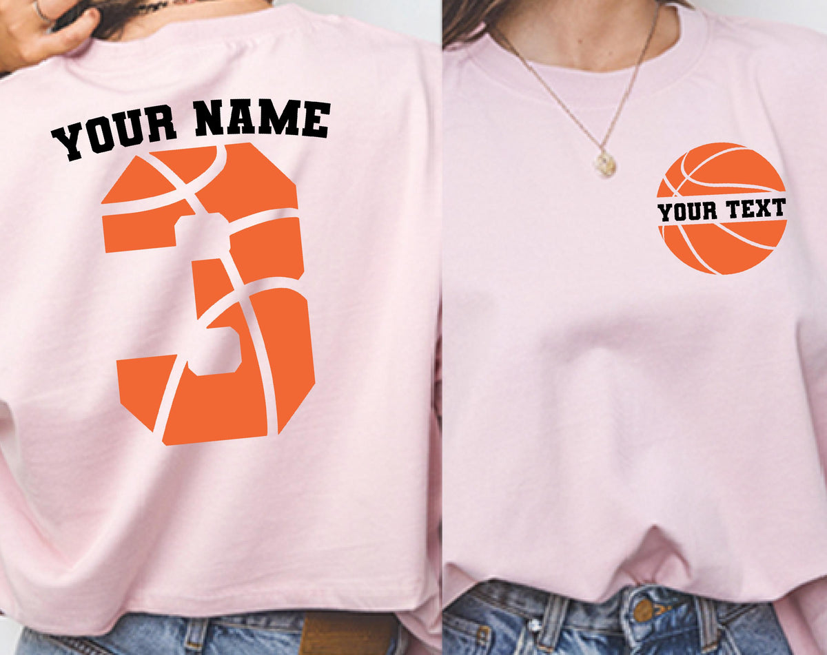 May include: A light pink t-shirt featuring a basketball-themed design. The back displays the text YOUR NAME above a large orange basketball-patterned number 3. The front left chest shows a small orange basketball graphic with the text YOUR TEXT.