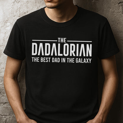 May include: Black t-shirt with the text "THE DADALORIAN THE BEST DAD IN THE GALAXY" in white. The shirt is a crew neck style and appears to be made of a soft material. The text is centered on the chest.
