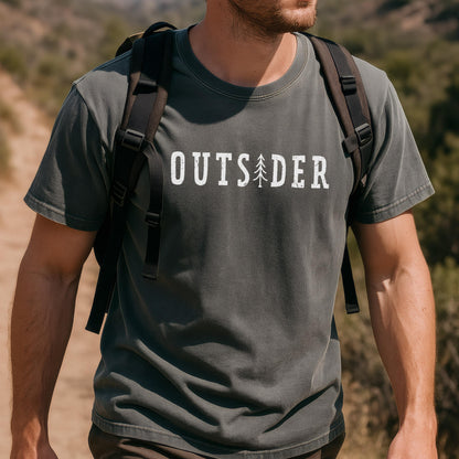 May include: A charcoal gray short-sleeve t-shirt featuring the white text OUTSIDER printed across the chest, with a stylized pine tree graphic replacing the letter I. The shirt is worn with a black backpack featuring adjustable shoulder straps.