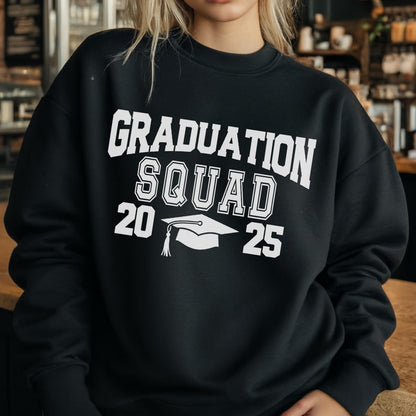 May include: Black crewneck sweatshirt with the text "GRADUATION SQUAD 2025" in white block letters. A white graduation cap graphic is centered below the word "SQUAD". The sweatshirt is a solid black color.