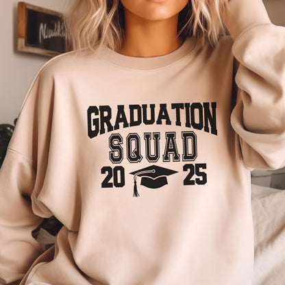 May include: A beige sweatshirt with the words "GRADUATION SQUAD 20 25" in bold black letters. A graduation cap graphic is centered below "SQUAD". The sweatshirt is a neutral color, suitable for various outfits.
