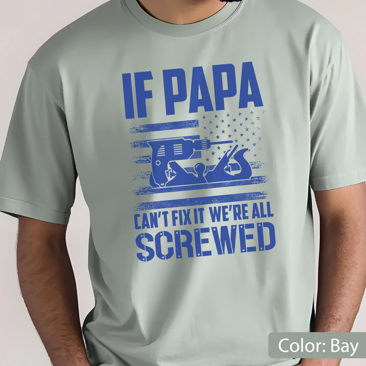 May include: A light green t-shirt with the text "IF PAPA CAN'T FIX IT WE'RE ALL SCREWED" in blue. The design includes a blue drill and a hand plane, set against a blue and white star and stripe background.