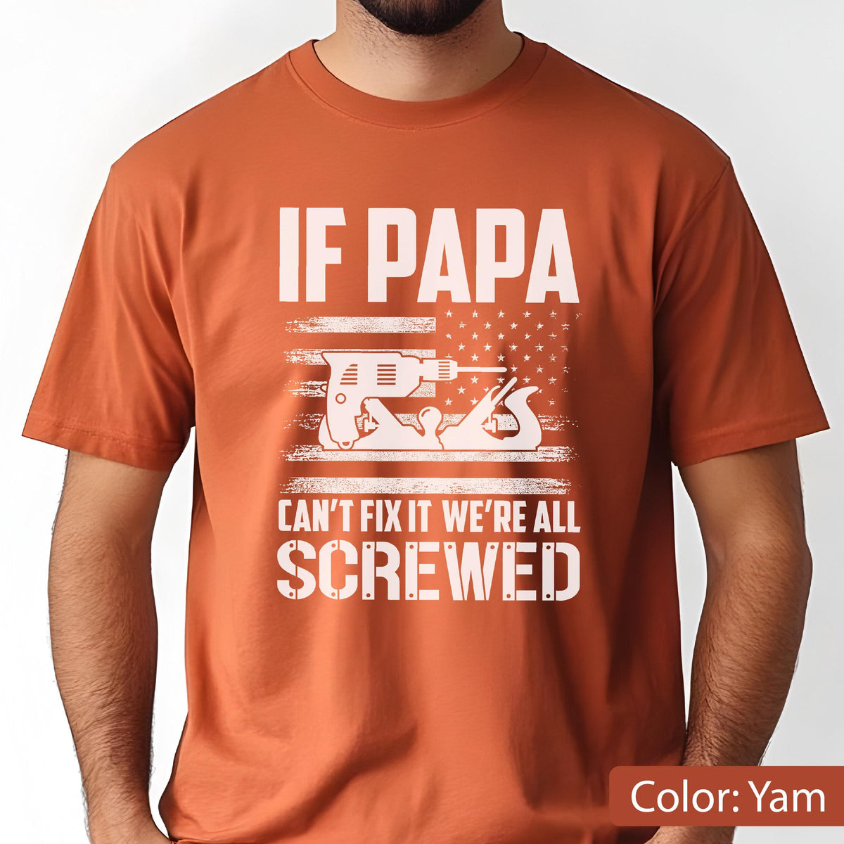 May include: A yam-colored t-shirt with the text "IF PAPA CAN'T FIX IT WE'RE ALL SCREWED" in white. The design includes a drill and a hand plane, set against a stylized American flag.
