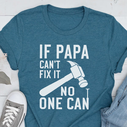 May include: Teal t-shirt with the text "IF PAPA CAN'T FIX IT NO ONE CAN" in white, along with a hammer and nail graphic. A gray sneaker and denim jeans are visible in the image.