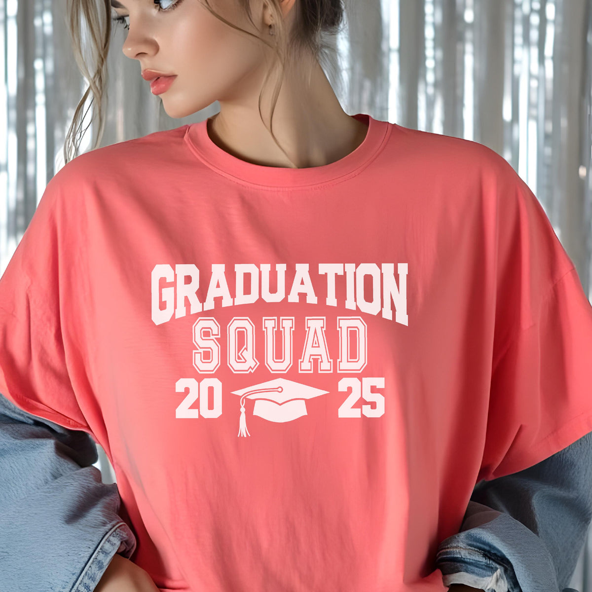 May include: Coral-colored t-shirt with the text "GRADUATION SQUAD 2025" in white block letters. A graduation cap graphic is centered below the text. The shirt is made of a soft material.