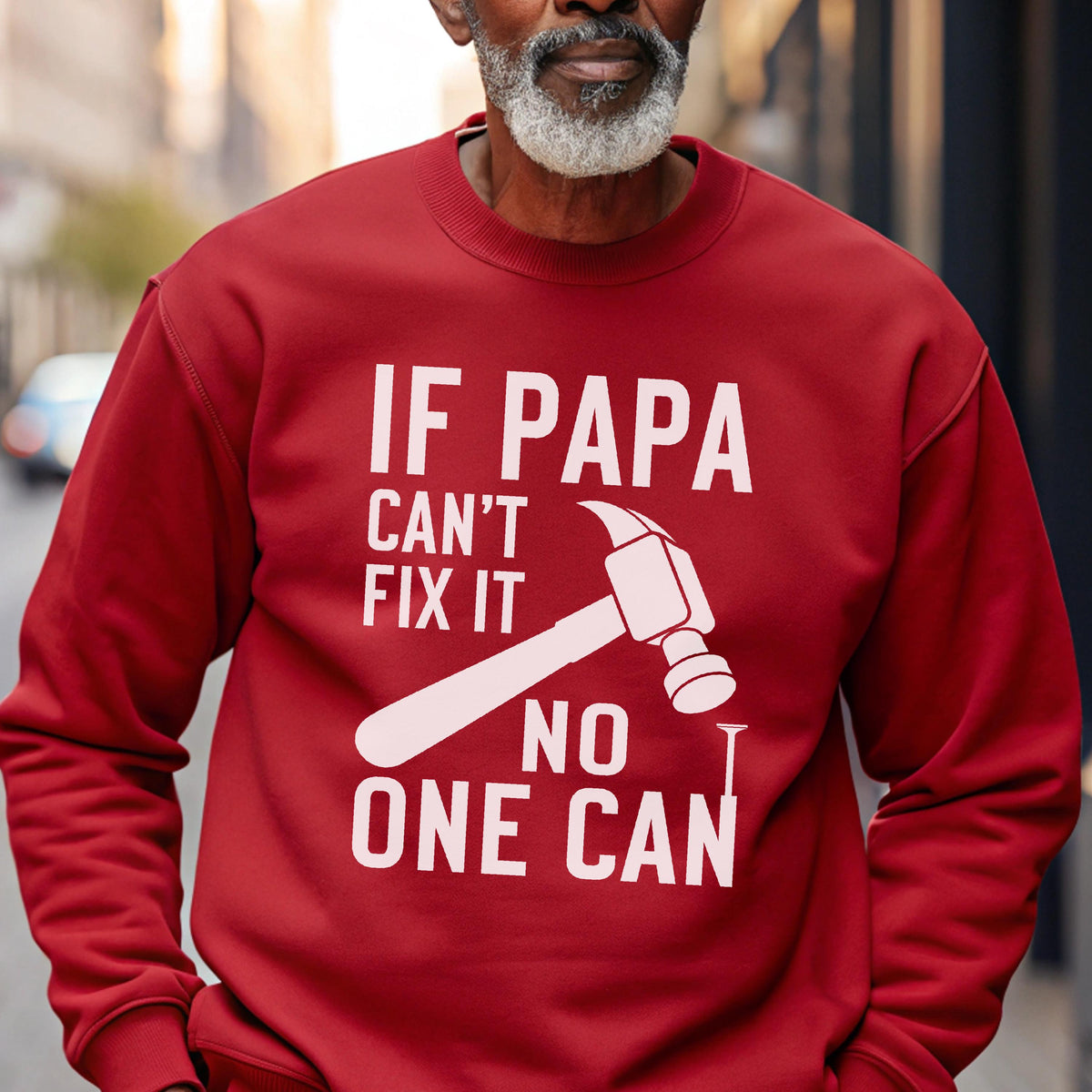May include: A red sweatshirt with the text "IF PAPA CAN'T FIX IT NO ONE CAN" in white. A white hammer graphic is featured in the center of the text. The sweatshirt is a solid color and has long sleeves.