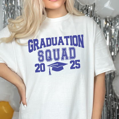 May include: White t-shirt with the text "GRADUATION SQUAD 2025" in blue. The design includes a graduation cap graphic. The shirt is a casual style, suitable for graduation celebrations.