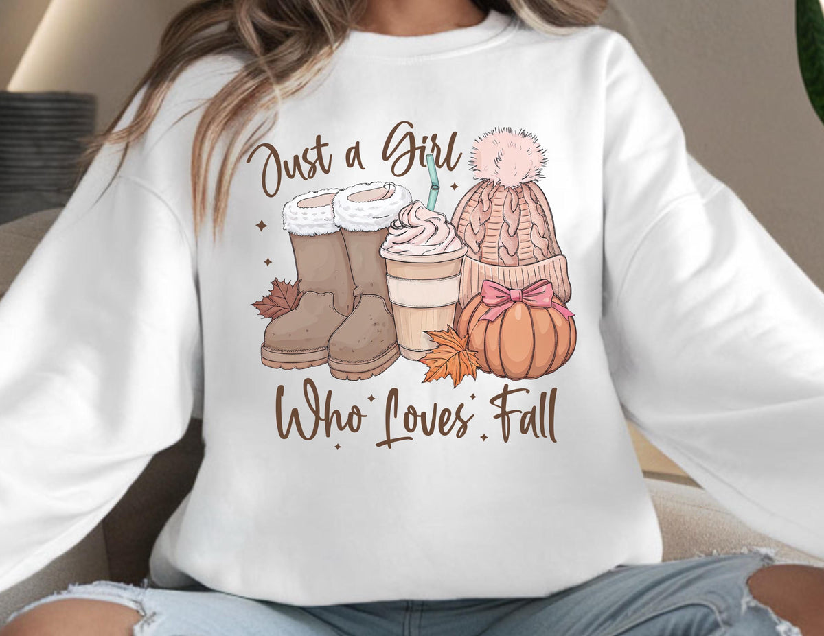 May include: White sweatshirt with a fall-themed graphic. The graphic includes brown boots, a coffee cup, a pink knit hat, and a pumpkin with a pink bow. The text reads "Just a Girl Who Loves Fall."