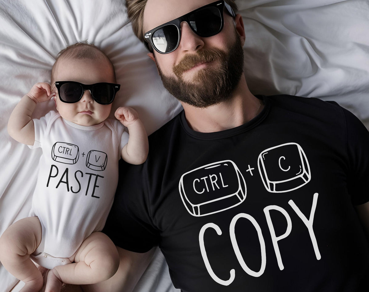 May include: A baby in a white onesie and an adult in a black t-shirt, both wearing black sunglasses. The onesie says "CTRL + V PASTE" in black text. The t-shirt says "CTRL + C COPY" in white text.