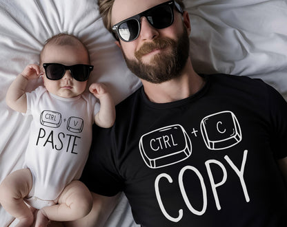 May include: A baby in a white onesie and an adult in a black t-shirt, both wearing black sunglasses. The onesie says "CTRL + V PASTE" in black text. The t-shirt says "CTRL + C COPY" in white text.