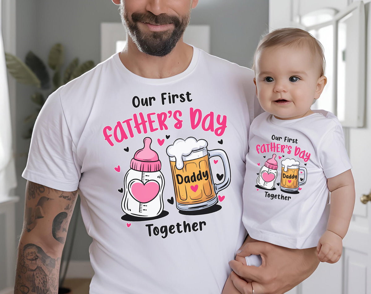 May include: White t-shirts with matching graphics for Father's Day. The shirts feature the text "Our First Father's Day Together" with illustrations of a baby bottle and a beer mug. The baby is wearing a matching shirt.