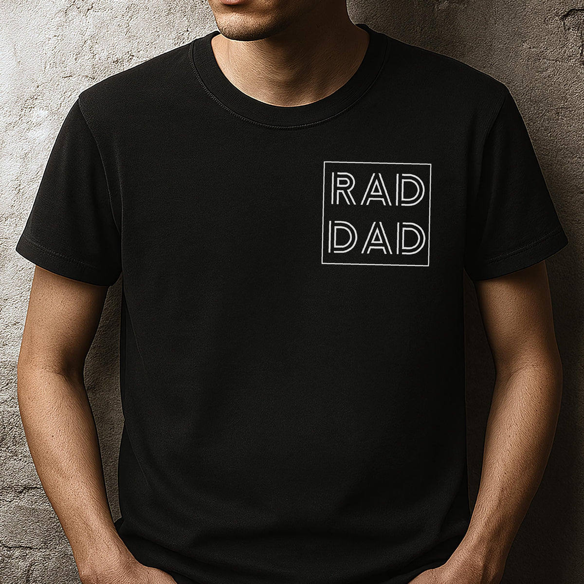 May include: Black t-shirt with the words "RAD DAD" in a white, minimalist font inside a white square. The shirt is a solid black color and has short sleeves.