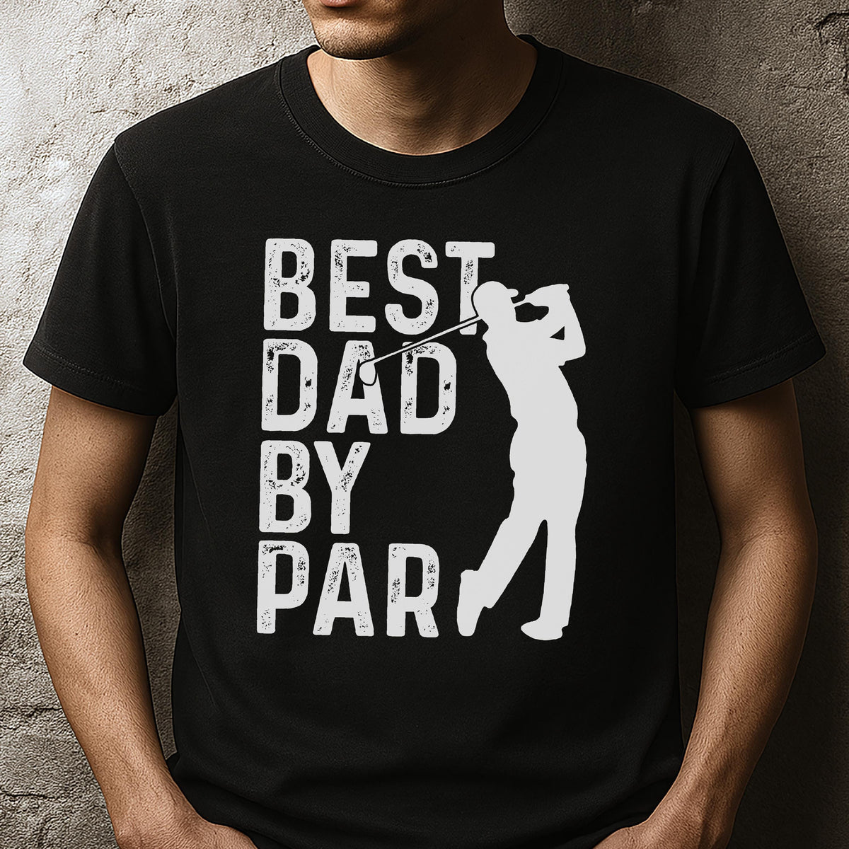 May include: A black short-sleeved t-shirt featuring a white graphic print. The design includes the text "BEST DAD BY PAR" in a distressed font, accompanied by a white silhouette of a golfer in a mid-swing position with a golf club.