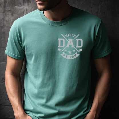 May include: A teal green t-shirt with a crew neck. The shirt features a white graphic on the chest that reads "BEST DAD BY PAY" with golf clubs and stars. The shirt is made of a soft material.