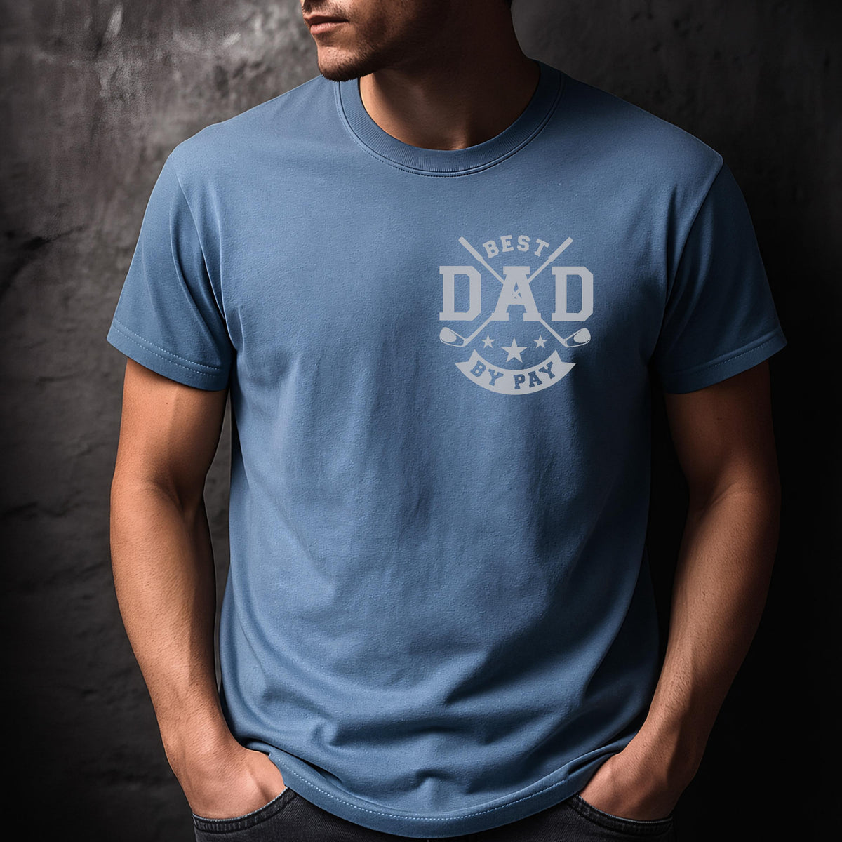 May include: A light blue t-shirt with the text "BEST DAD BY PAY" in white. The design includes golf clubs and stars. The shirt is a crew neck and has short sleeves.