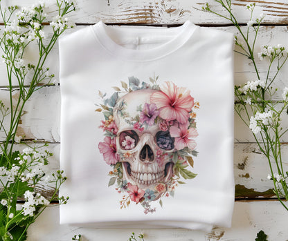 May include: White crewneck sweatshirt featuring a watercolor skull design adorned with pink, purple, and blue flowers. The floral skull graphic is centered on the front of the folded garment, creating a unique and artistic aesthetic.