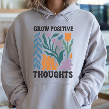 May include: A light gray hoodie with a front graphic that reads "GROW POSITIVE THOUGHTS." The graphic features colorful floral and abstract shapes in orange, blue, green, and pink. The hoodie has a drawstring hood and a front pocket.