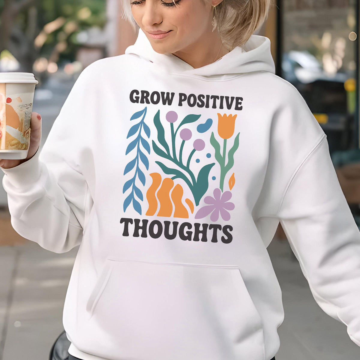 May include: White hoodie with a front pocket and the words "GROW POSITIVE THOUGHTS" in black. The graphic includes colorful floral and abstract shapes in blue, orange, green, and purple.