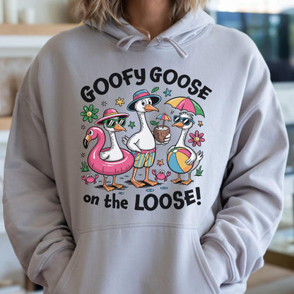 May include: A light gray hoodie featuring a graphic of three cartoon geese in sunglasses and beach attire. The text "GOOFY GOOSE on the LOOSE!" is printed above and below the geese. The geese are wearing a flamingo float, holding a coconut drink, and a beach ball.